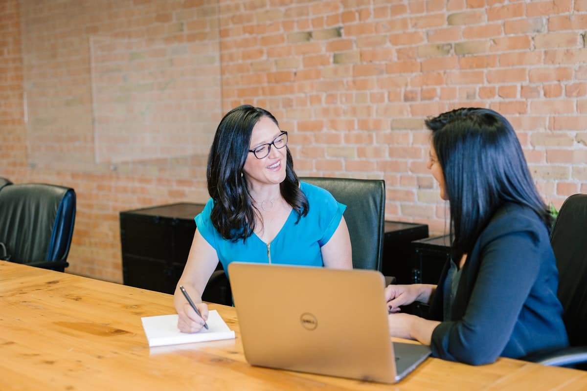 Two people in a genuine conversation across a table with a laptop, representing a family financial planning discussion