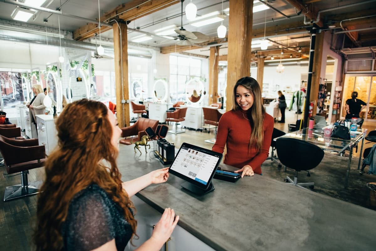 A candid small-business checkout moment between two people, representing a business owner's day-to-day focus