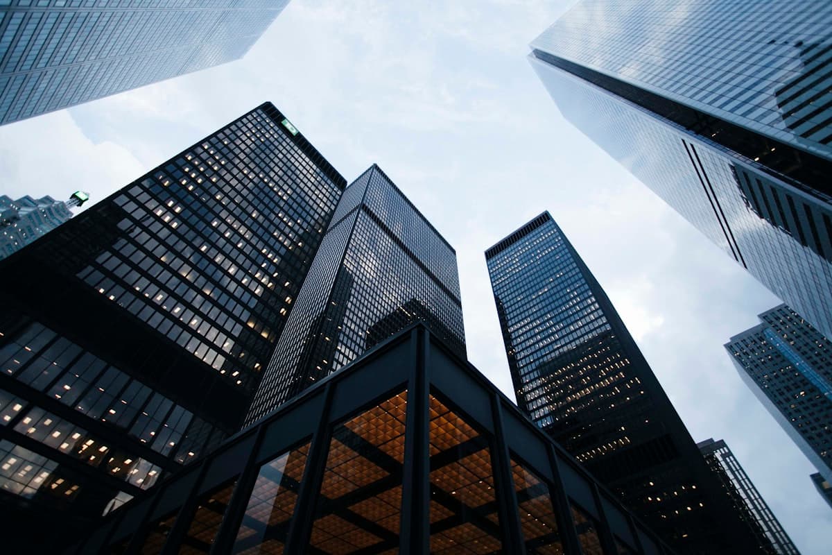 Dramatic upward view of financial district skyscrapers, representing ambition and long-term growth